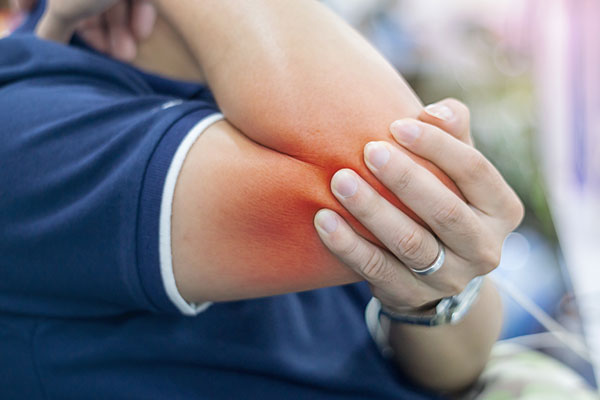 colour photo of a person holding their elbow as if in pain